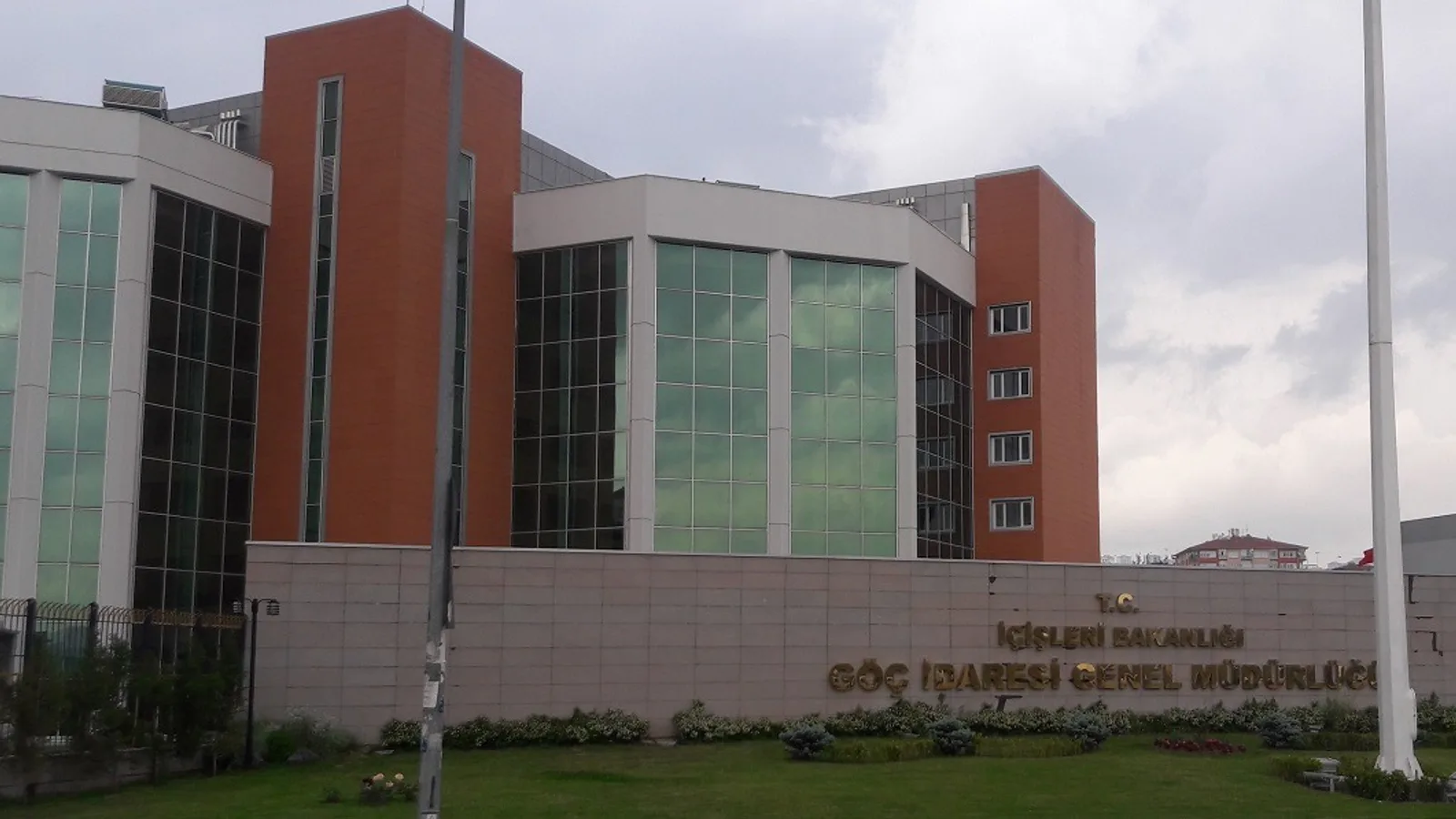 Kırmızı-yeşil mimarlıklı modern bina, ön tarafında 'Göç İdaresi Genel Müdürlüğü' tabelası