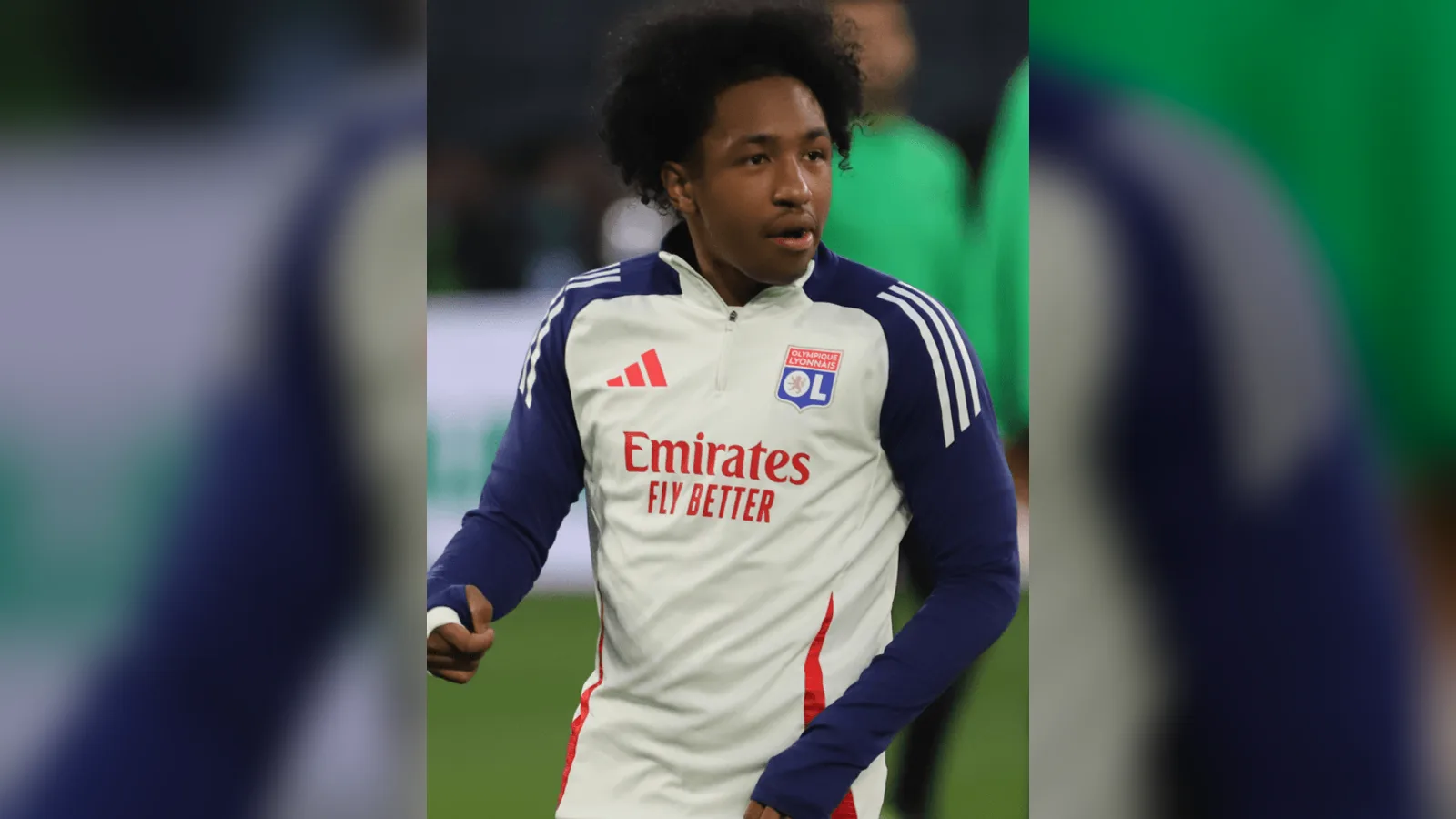Lyon antrenman kıyafetli futbolcu, yeşil sahada.