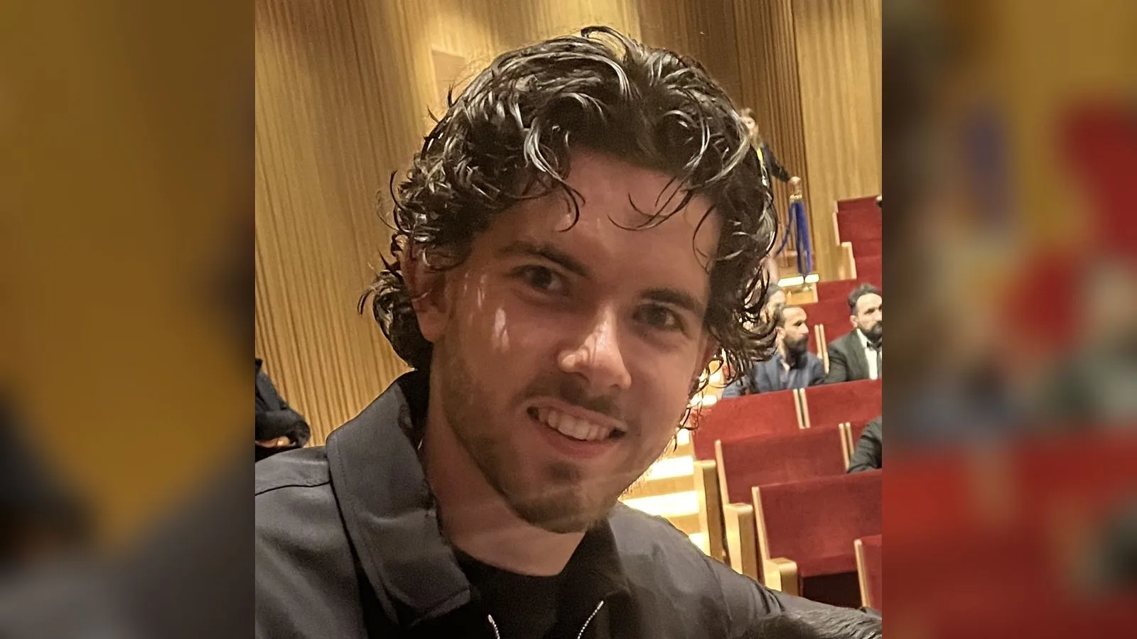 Siyah giysi, kıvırcık saçlı genç erkek, iç mekan, gülümsüyor.