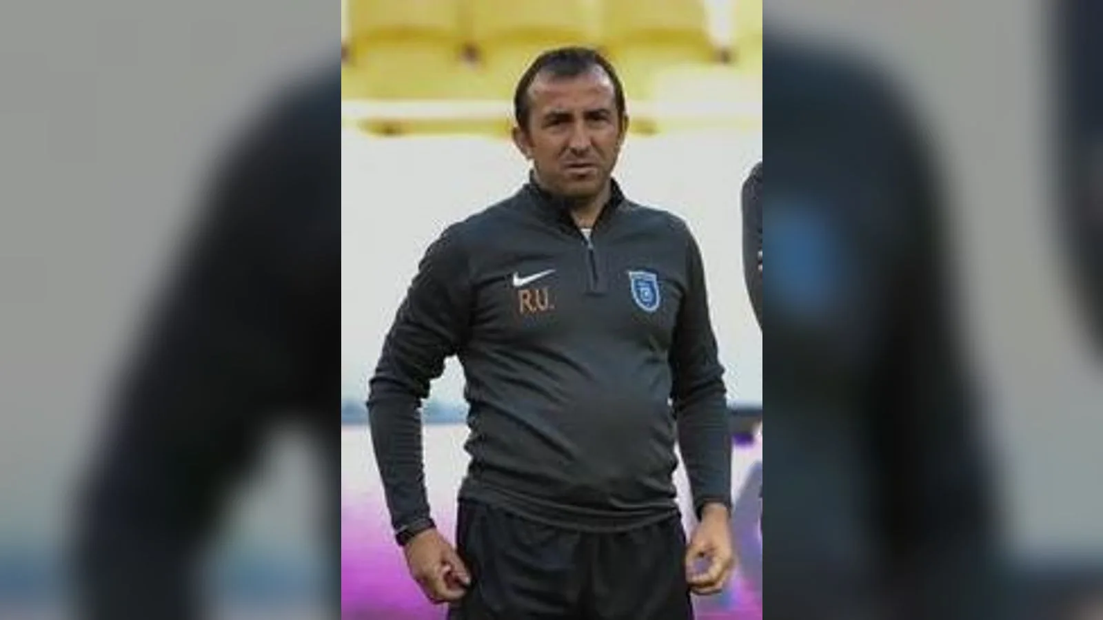 Siyah Nike antrenörlük ceketinde Göztepe rozeti, orta yaşlı adam.