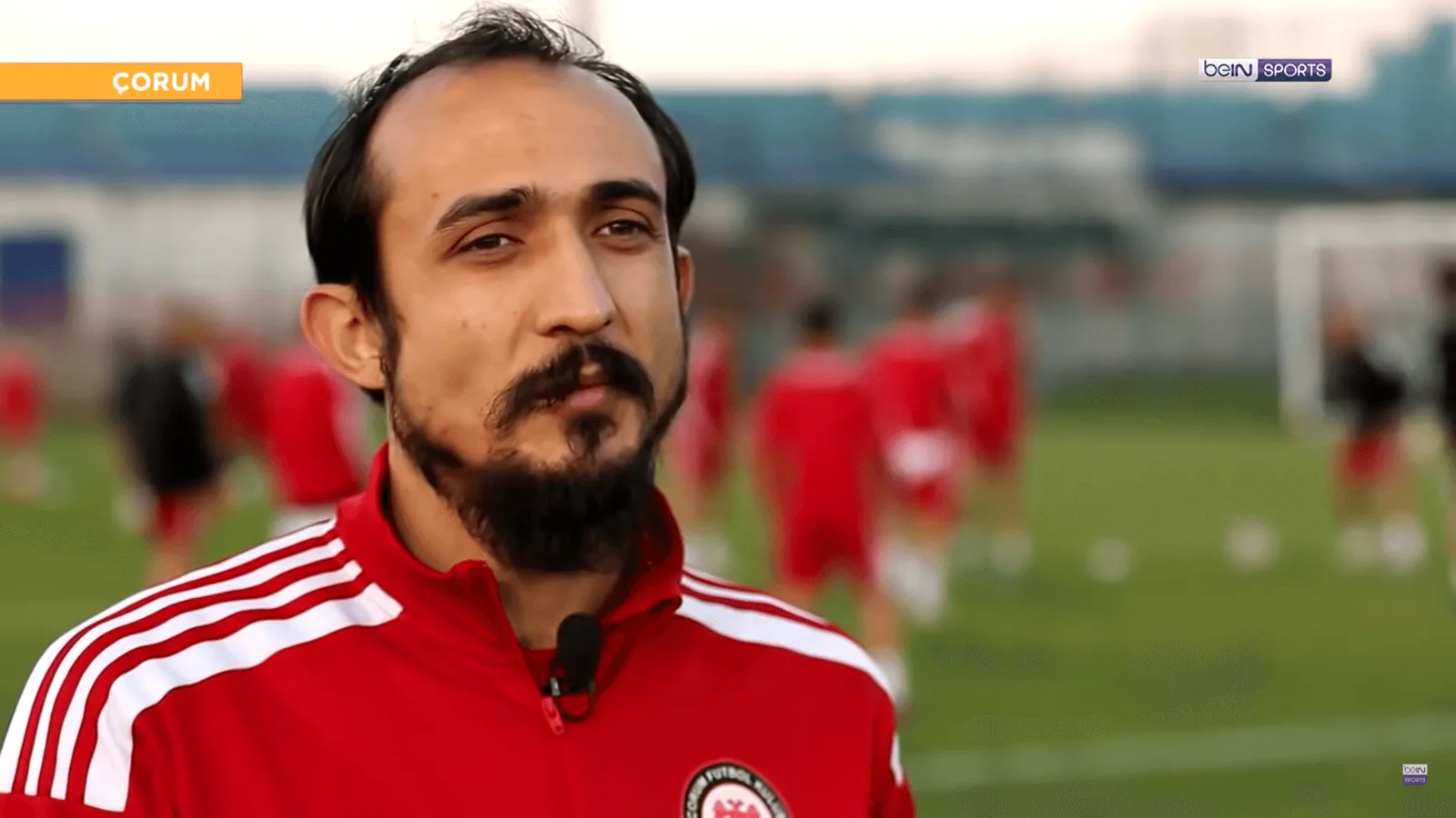 Çorum etiketiyle futbol sahasında kırmızı-beyaz üniformalı erkek oyuncu portresi.
