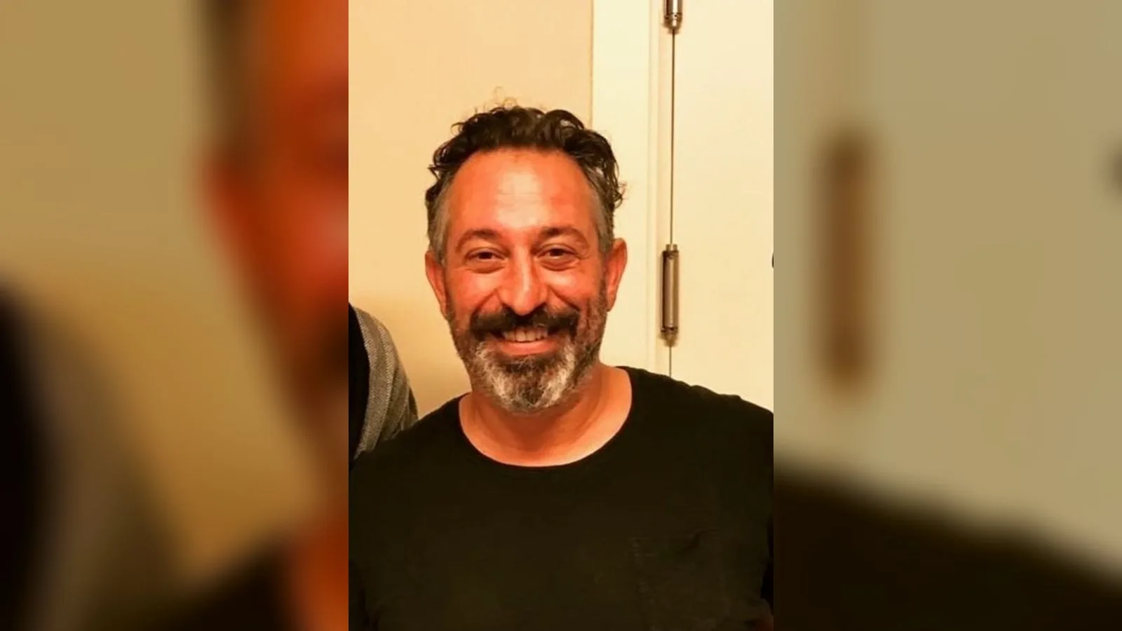 Siyah tişörtlü, sakallı erkek profil portresi gülümseme ifadesi.