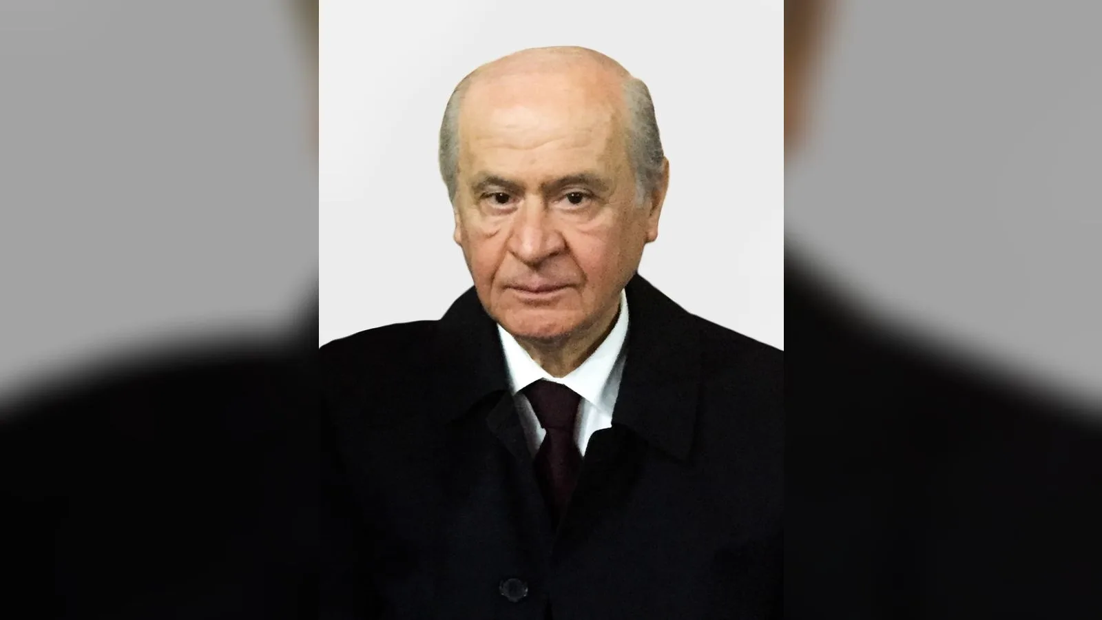 Beyaz saç, siyah ceket, ciddi ifadeli erkek portresi