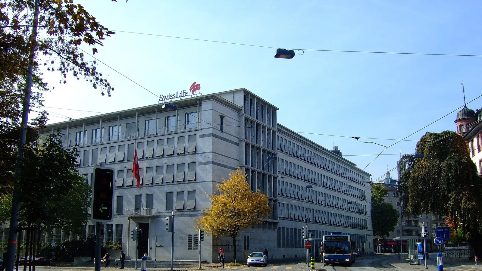 Swiss Life logolu ofis binasının cephesi, şehir caddesi görünümü.