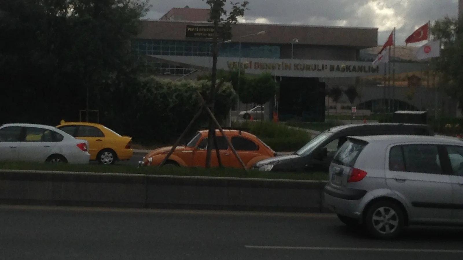 Kaza yaşamış turuncu ve gri otomobillerin görülü olduğu sokak ve bina.