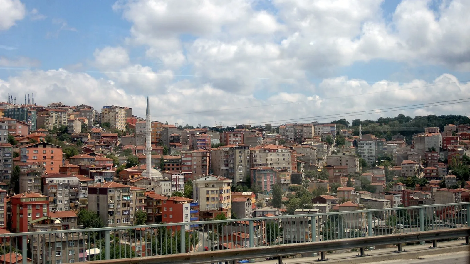 İstanbul ilçesinin dağ eteği yerleşim alanı, renkli apartmanlar ve camii silueti.