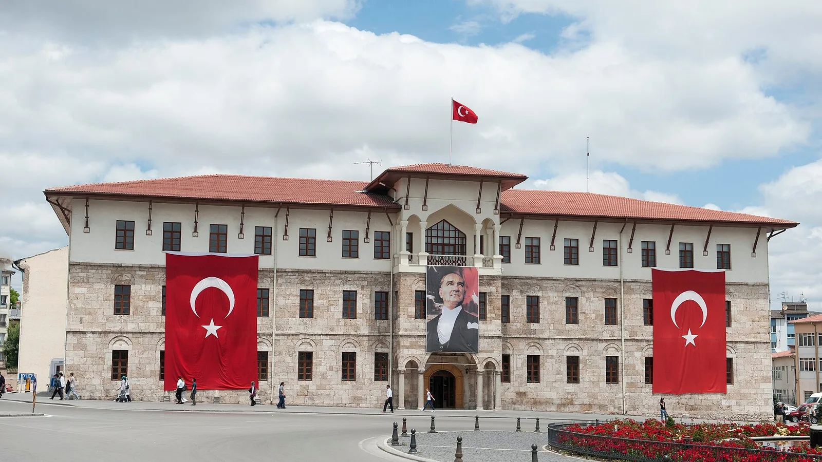 Taş yapı, iki büyük Türk bayrağı ve pano, Türk bayrağı çatıda.