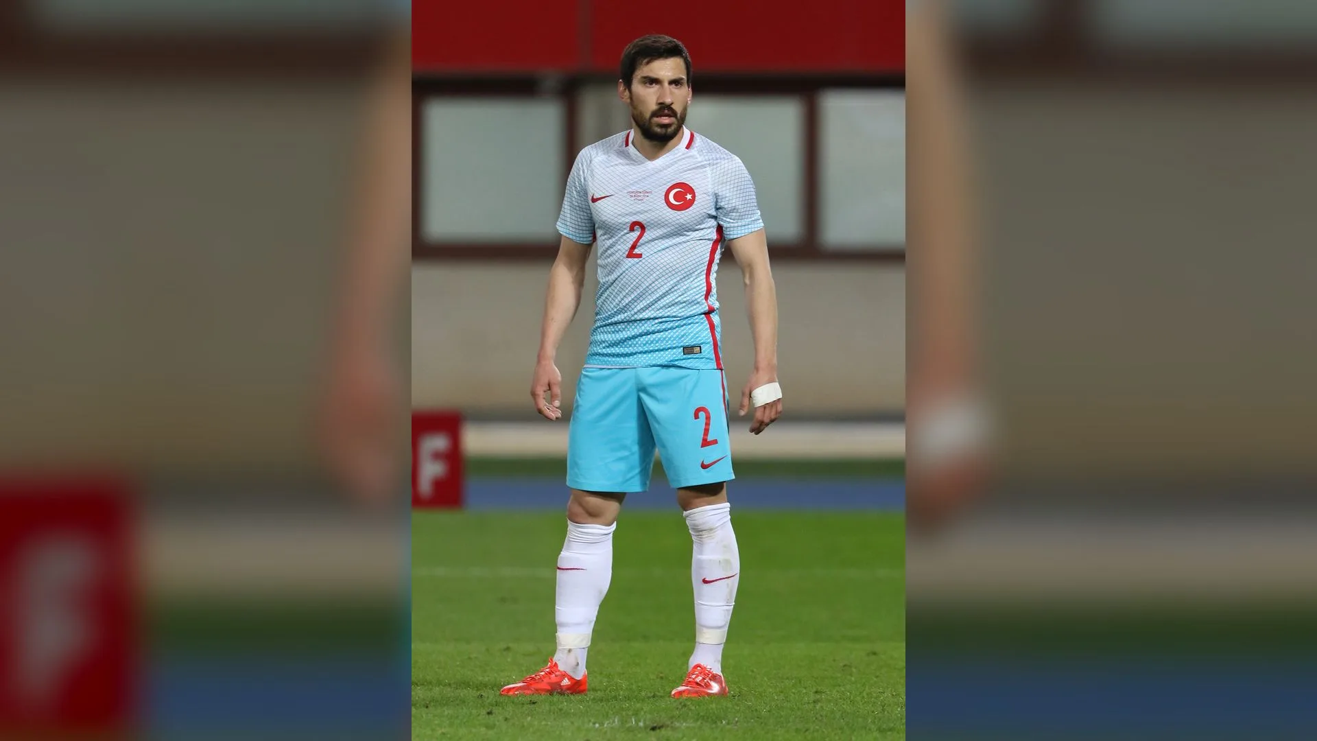 Açık mavi 2 numaralı formalı sakallı bir futbolcu sahada ayakta duruyor