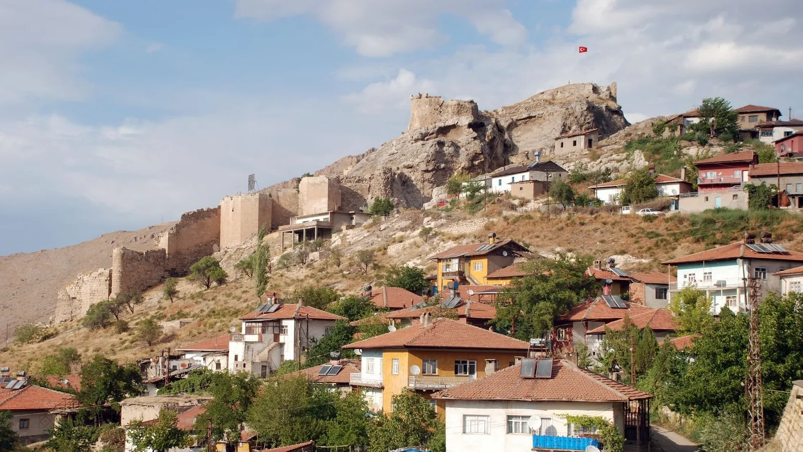 Divriği'nin taş kalesi ve eteklerindeki geleneksel evleriyle dolu dağ manzarası.