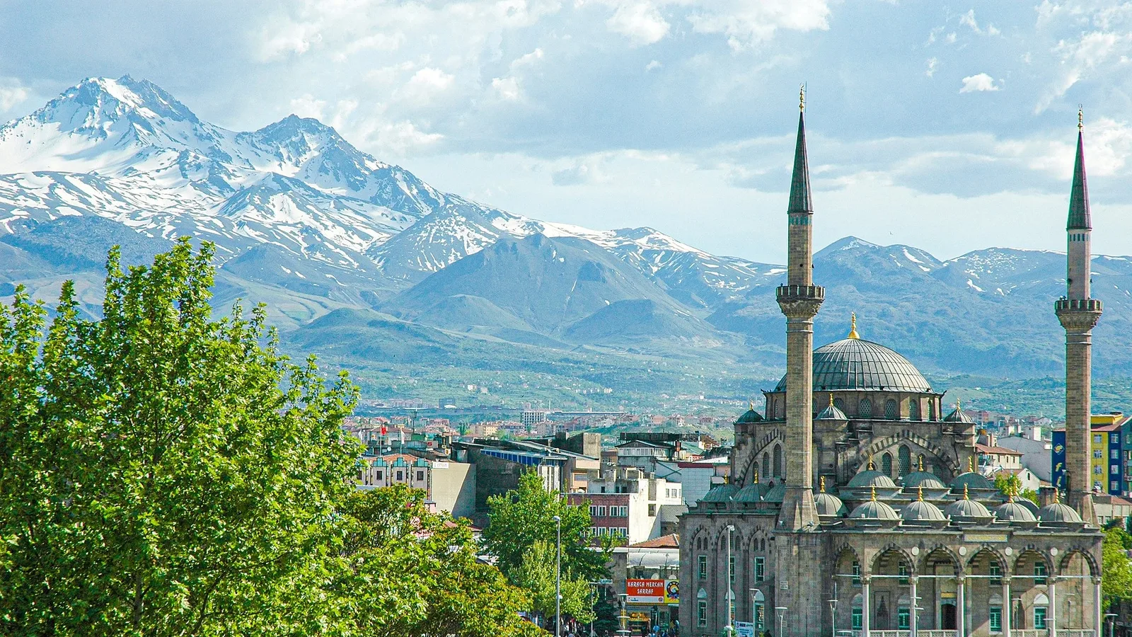 Erciyes Dağı'nın snowy peaks'i, ön planda Kayseri şehir manzarası ve cami.