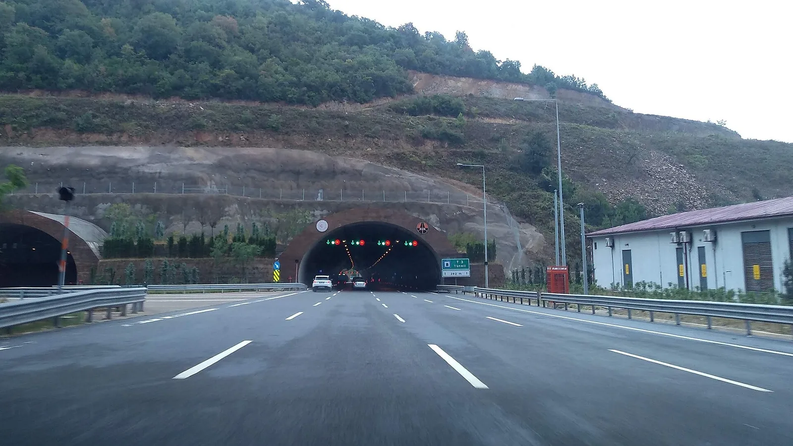 Kuzey Marmara Otoyolu tünel girişi, çok şeritli yol ve orman yamaçları.