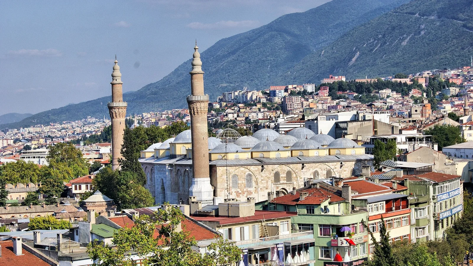 Bursa şehrinin merkezinde iki minare ve yapıların bulunduğu manzara.