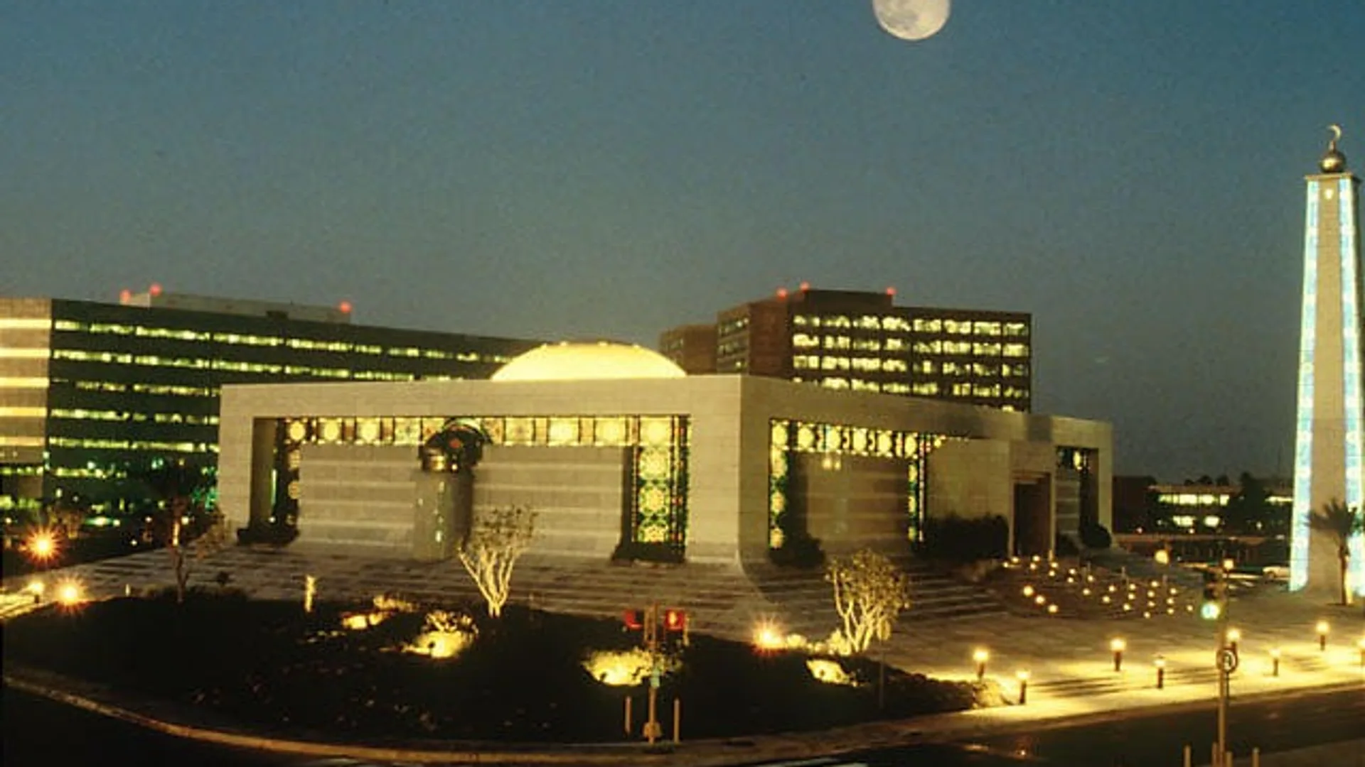 Gece aydınlandırılmış modern bir devlet binası, arkasında şehir rektörlüğü.