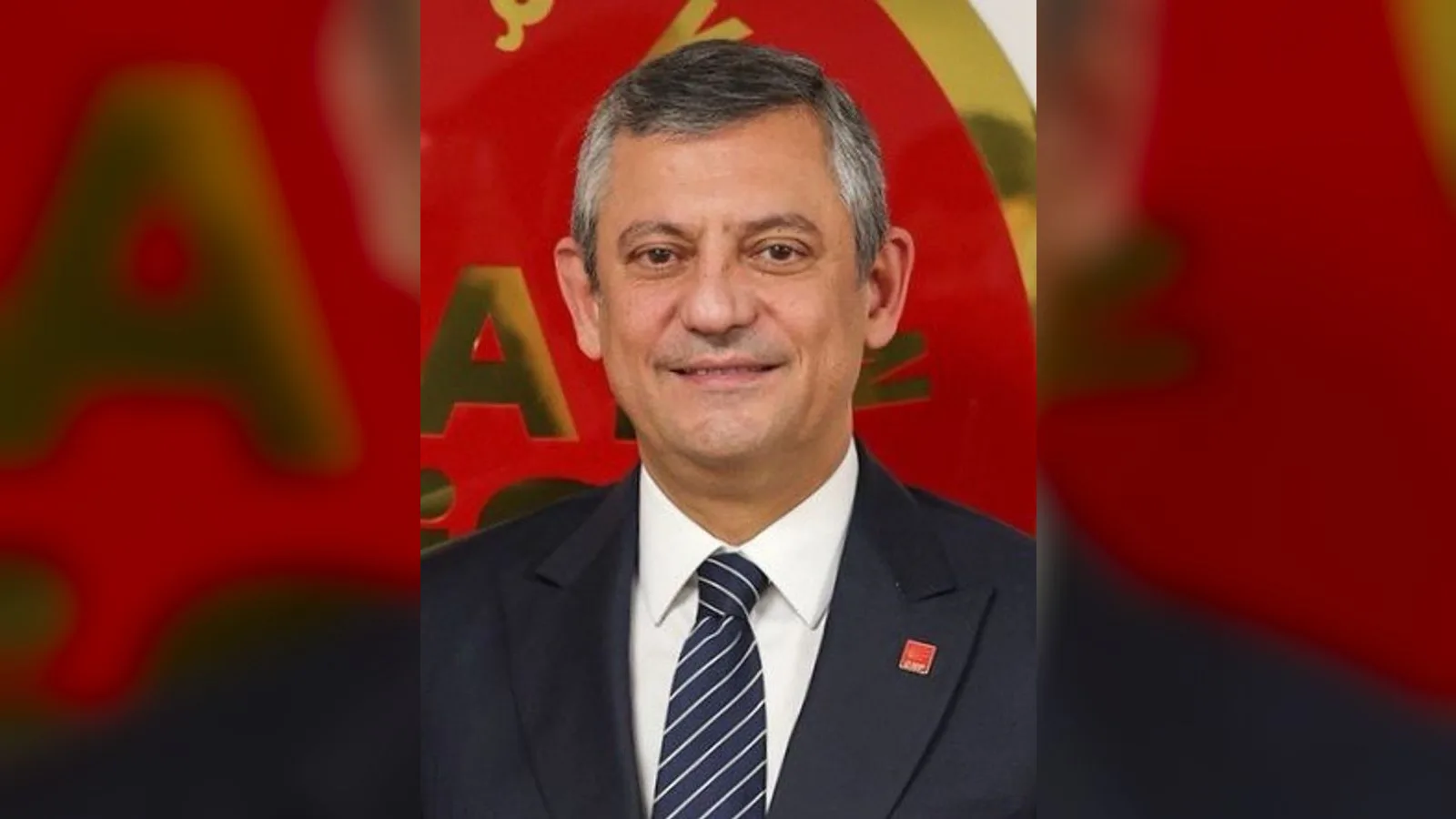 Takım elbiseli, kravatlı orta yaşlı adam resmi portresi kırmızı arkaplan önünde.