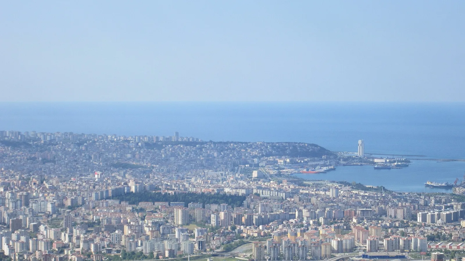 Samsun kıyısında dalgalanan deniz ve limanda mavna, kargo gemileri.