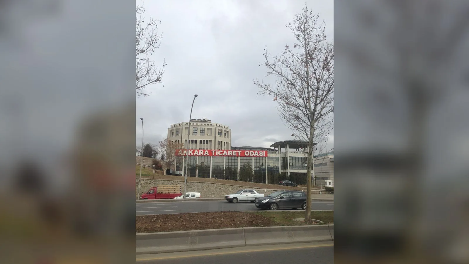 Ankara Ticaret Odası binası sarı ışıklandırmalı, bulutlu gün.