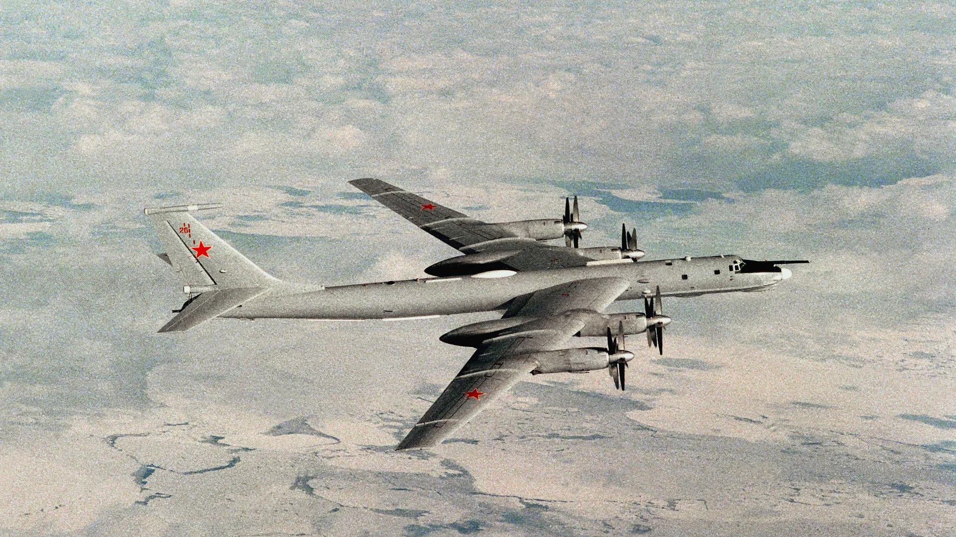 Kızıl yıldızlı, pervaneli gri bir bombardıman uçağı buzlu denizin üzerinde uçuyor