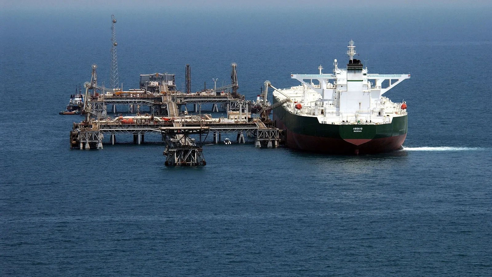 Denizde offshore petrol platformu yanında beyaz-siyah renkli tanker gemisi.