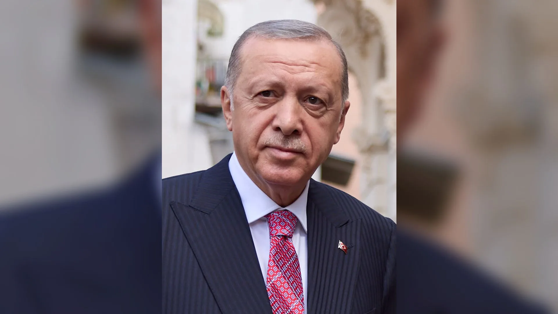 Lacivert takım elbiseli, pembe kravatlı, gri saçlı yaşlı bir adamın portresi