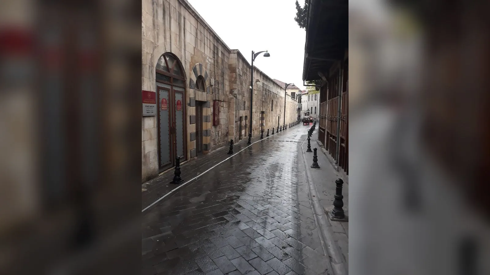 Taş binalar ve ıslak kaldırımla eski bir sokak görüntüsü.