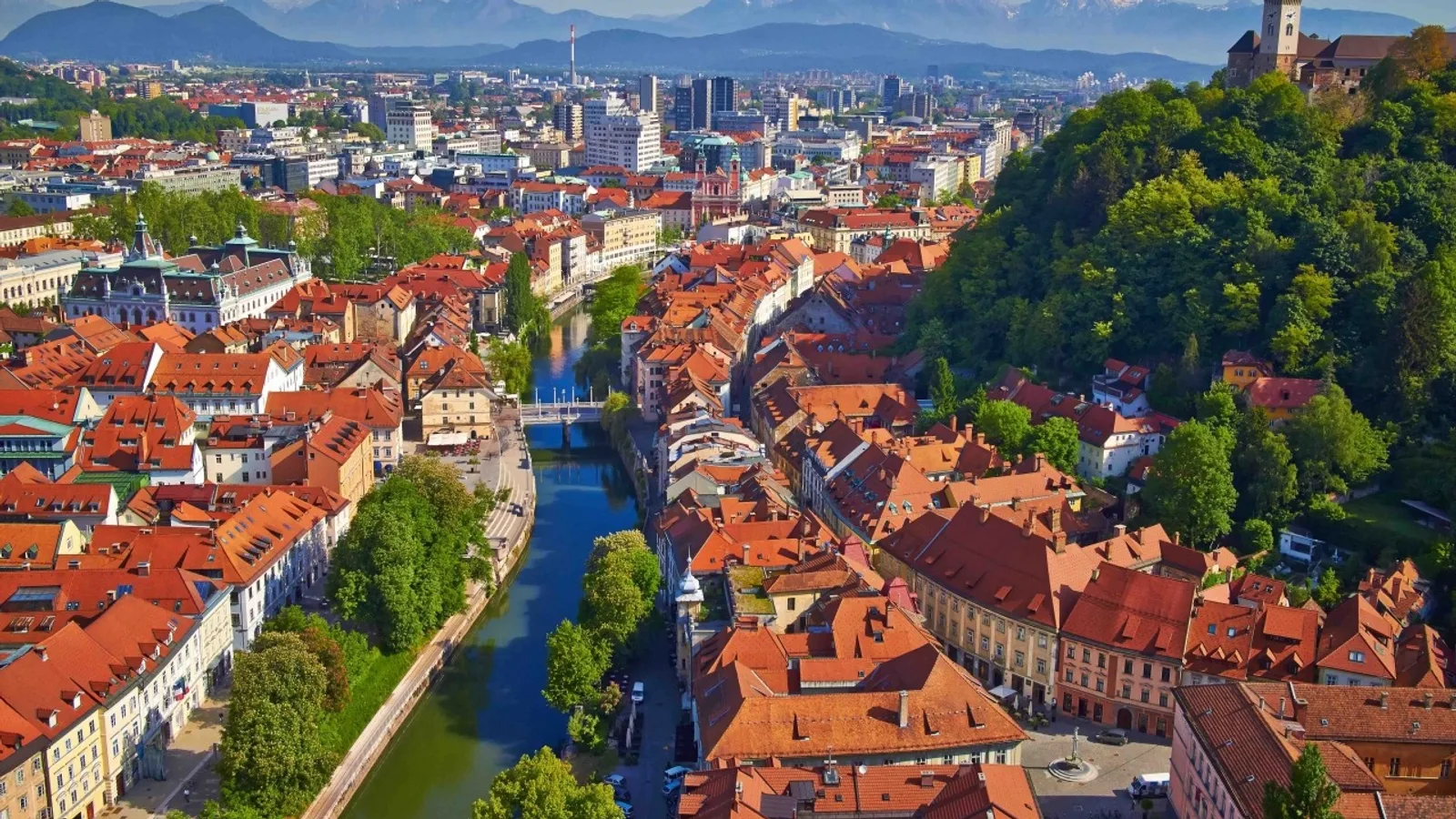 Ljubljana'nın kuş bakışı görünümü, turuncu çatılar ve mavi nehir görülmektedir.