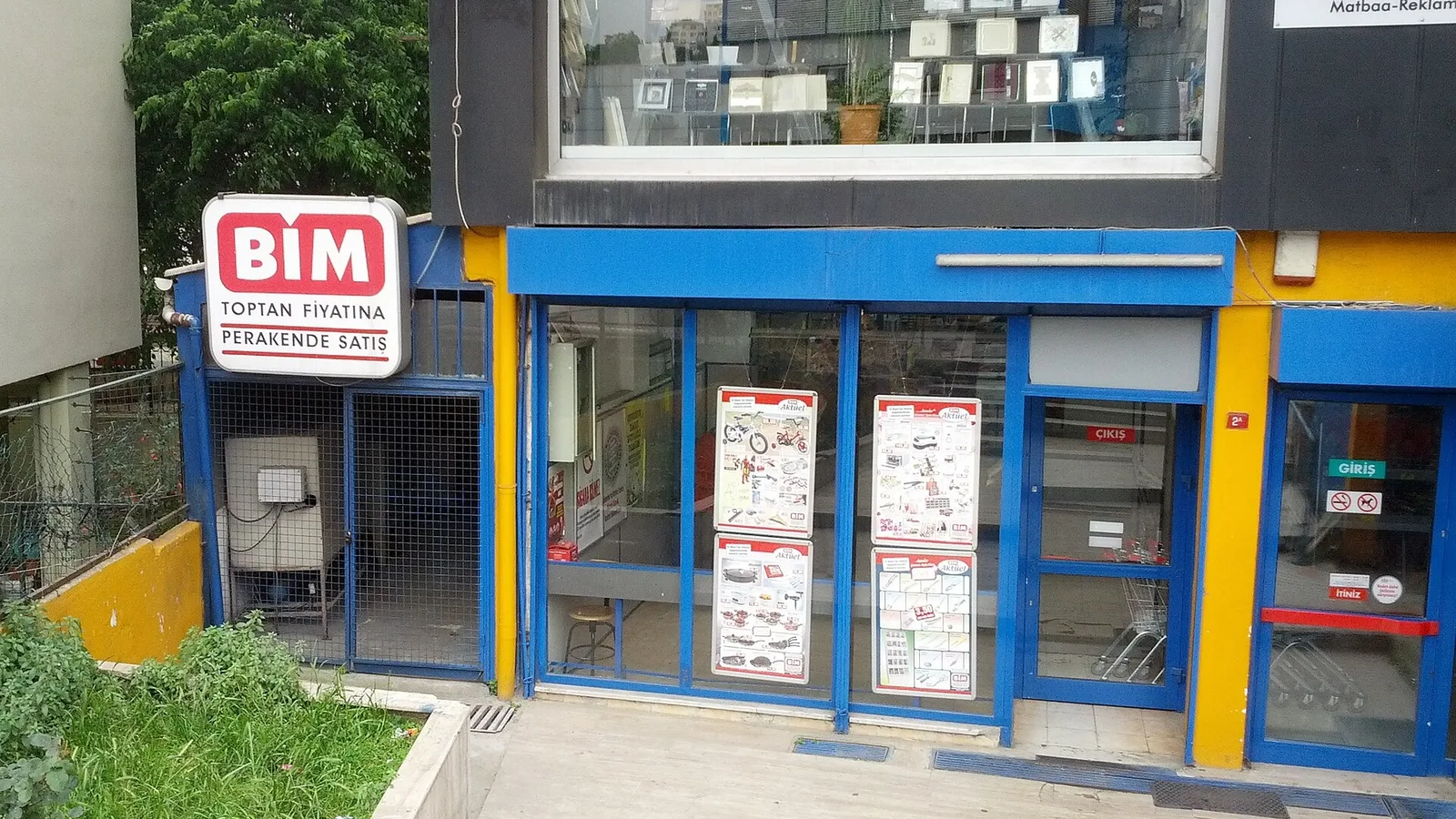 BİM mağazasının mavi ve sarı cephe görünümü, giriş kapısı ve vitrin panoları.