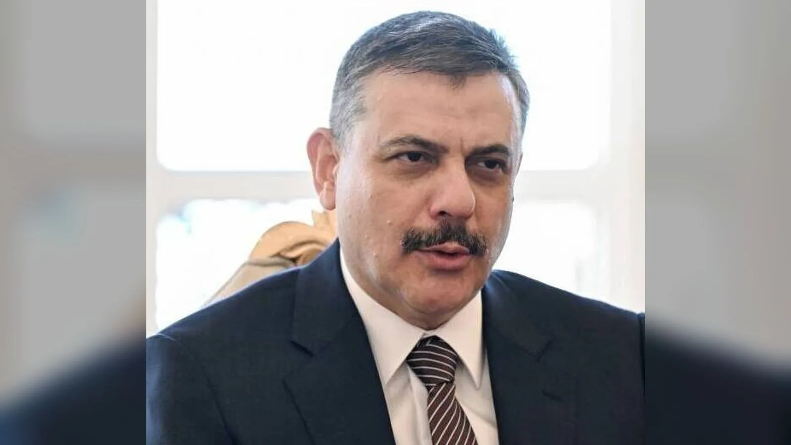 Koyu renk takım elbiseli, bıyıklı bir erkek yüz portresi stüdyo aydınlatması altında.