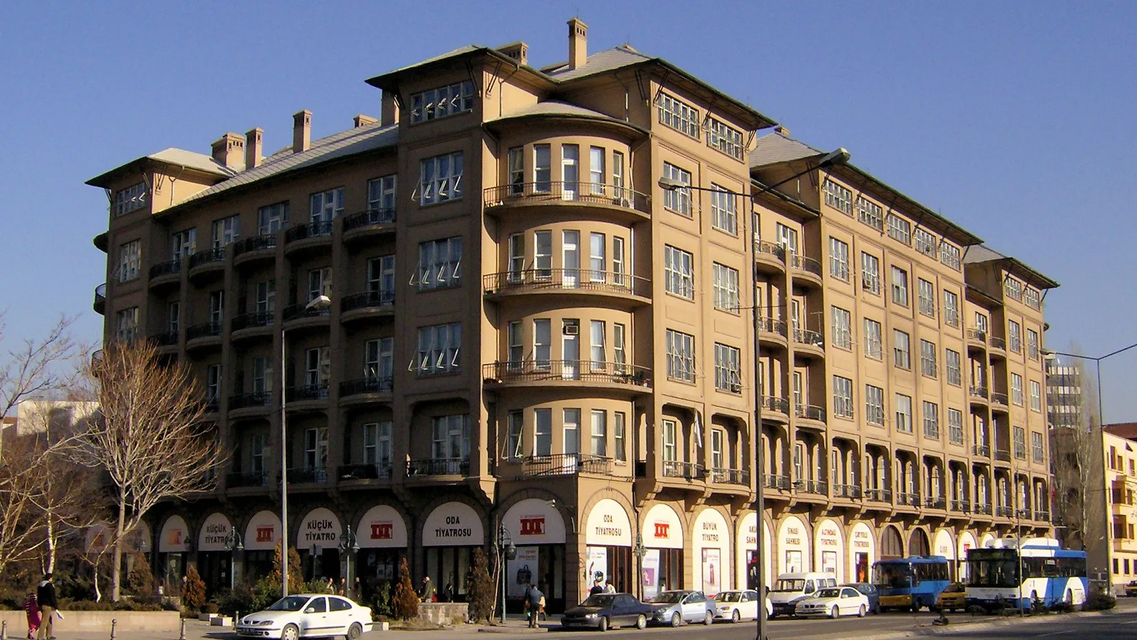 Bej ve siyah renklerde, balkonlu klasik apartman binası cadde cephesinde.