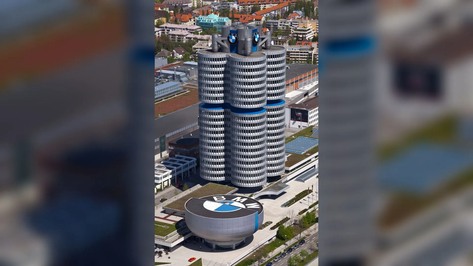 Silindir biçimli yüksek BMW genel merkez binası ve önünde logolu yuvarlak müze yapısı