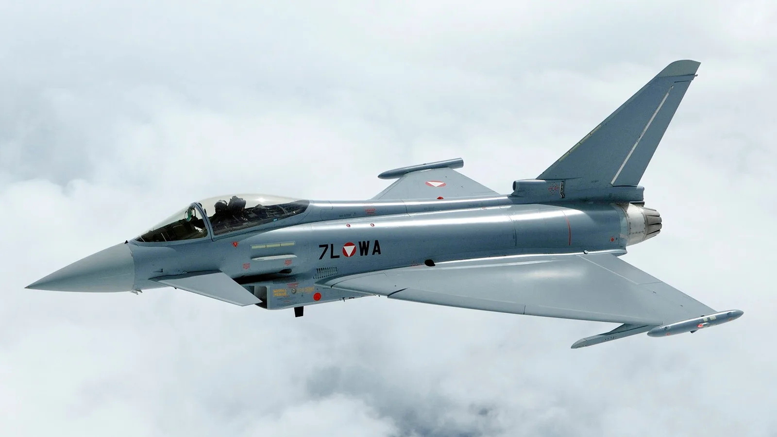 Eurofighter Typhoon savaş uçağı bulutlar arasında uçuş halinde, yan profil.