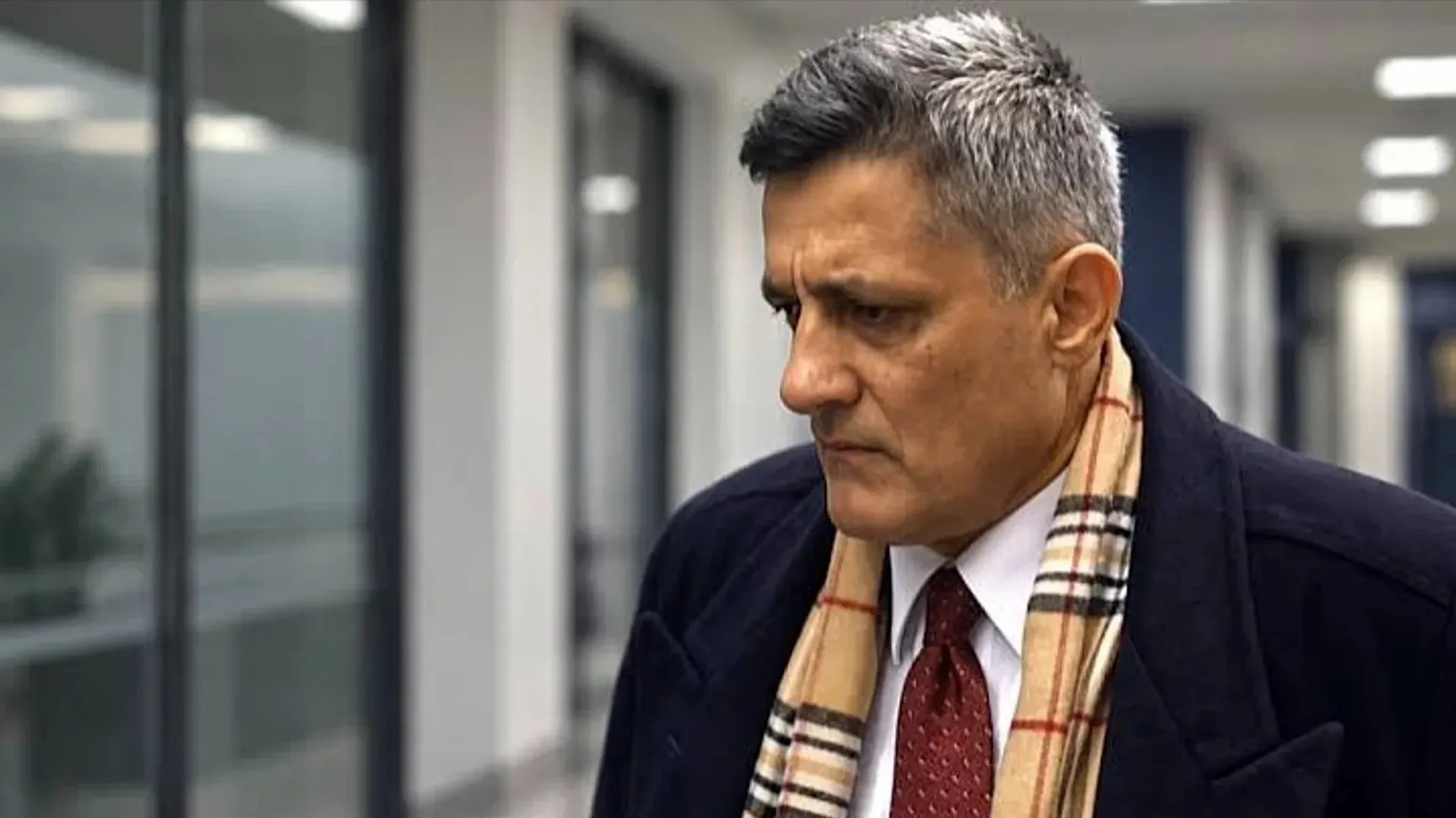 Eski MİT görevlisi Kaşif Kozinoğlu, lacivert kaban ve ekose atkısıyla bir adliye koridorunda yürürken