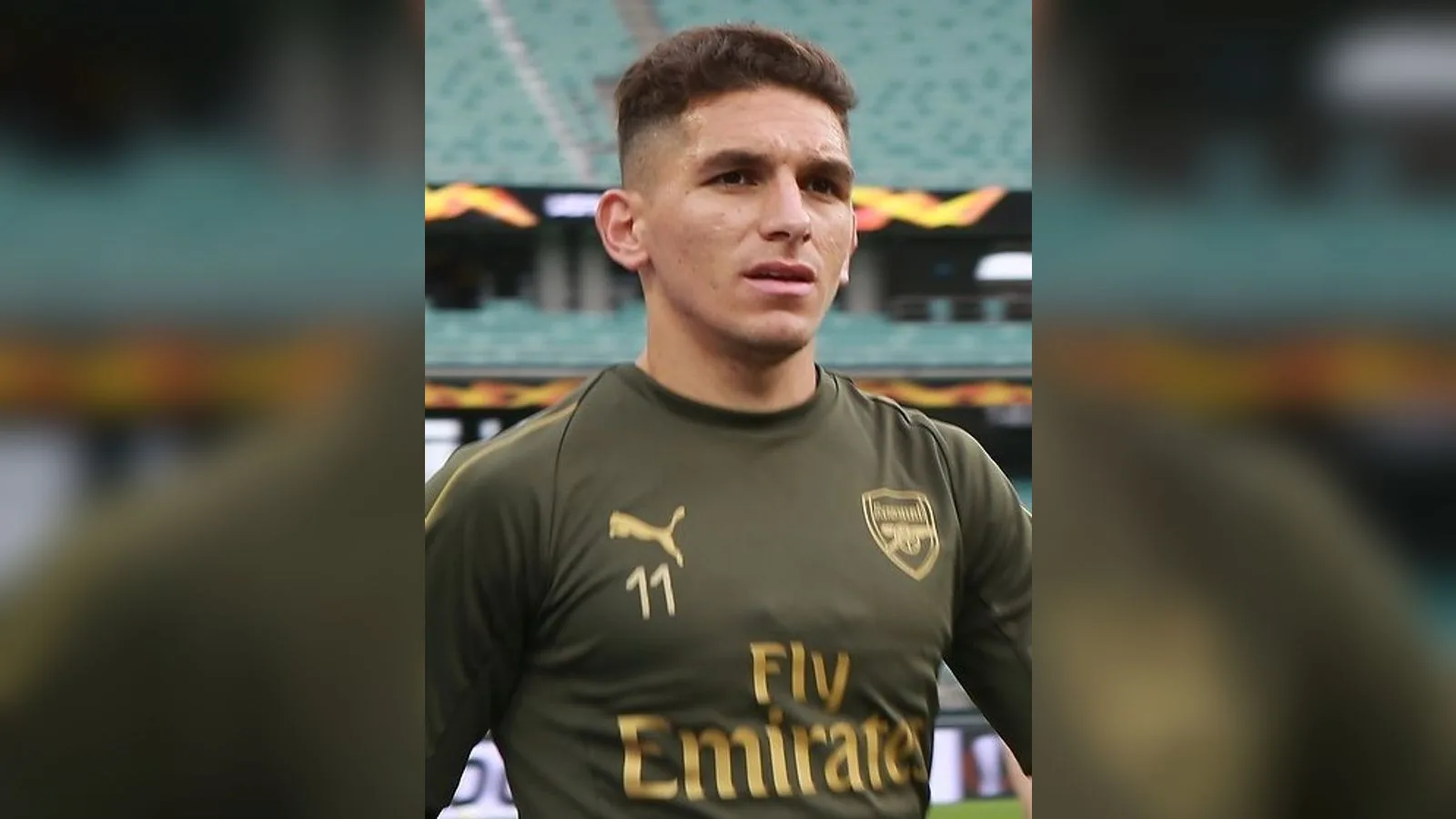 Arsenal forması giymiş, numarası 11 olan futbolcu çim saha arka planında.