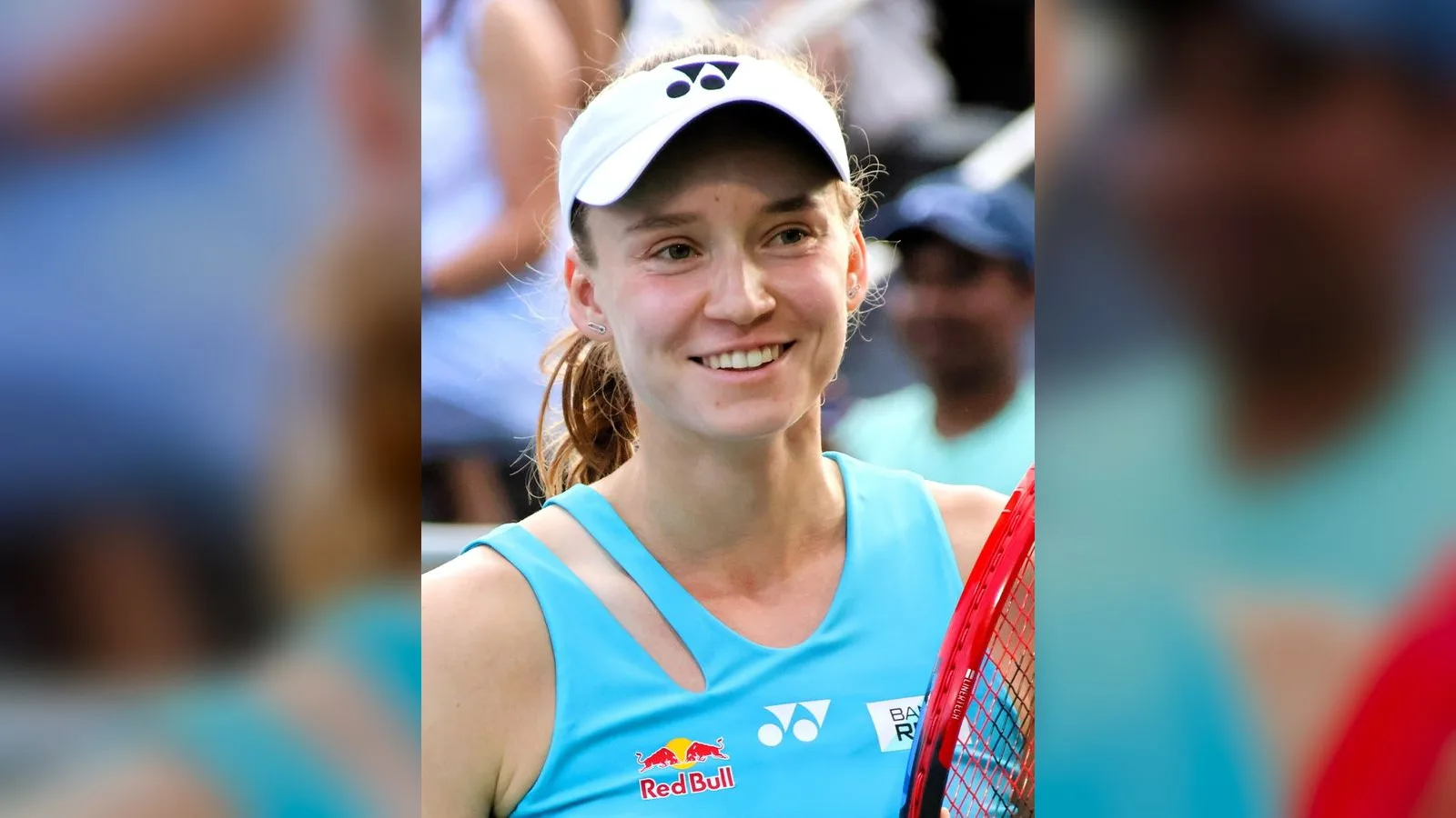 Beyaz şapkalı, mavi tenis elbiseli genç kadın, raket tutuyor.