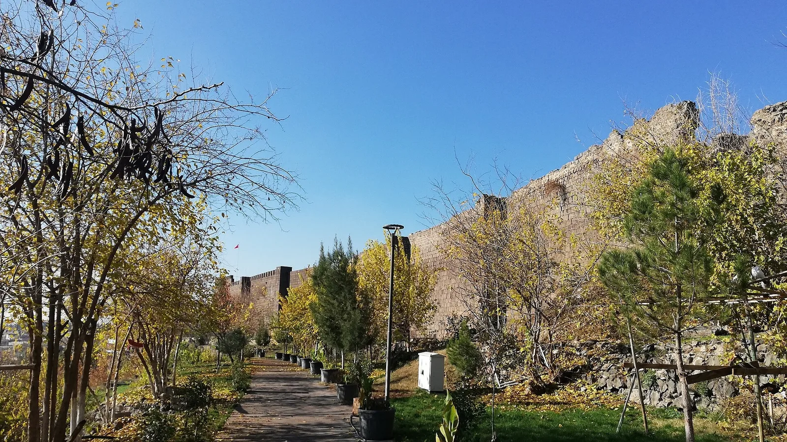 Diyarbakır surları ve park, yeşil ağaçlar, açık mavi gökyüzü.