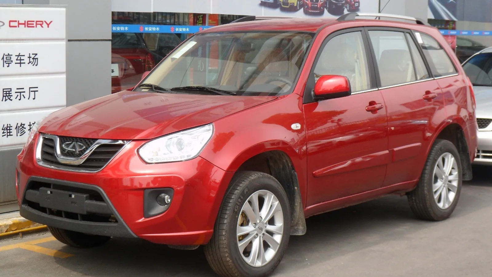Kırmızı Chery marka SUV, sergi alanında ön veya yan açıdan görünüyor.