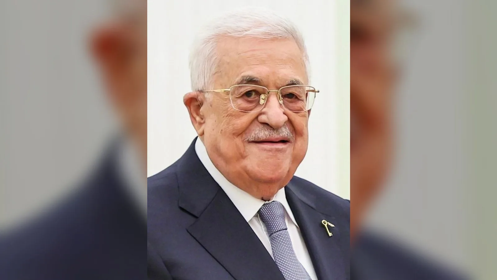 Gözlüklü, beyaz saçlı yaşlı bir adam resmi portresi, koyu takım elbise ve kravat giymiş.
