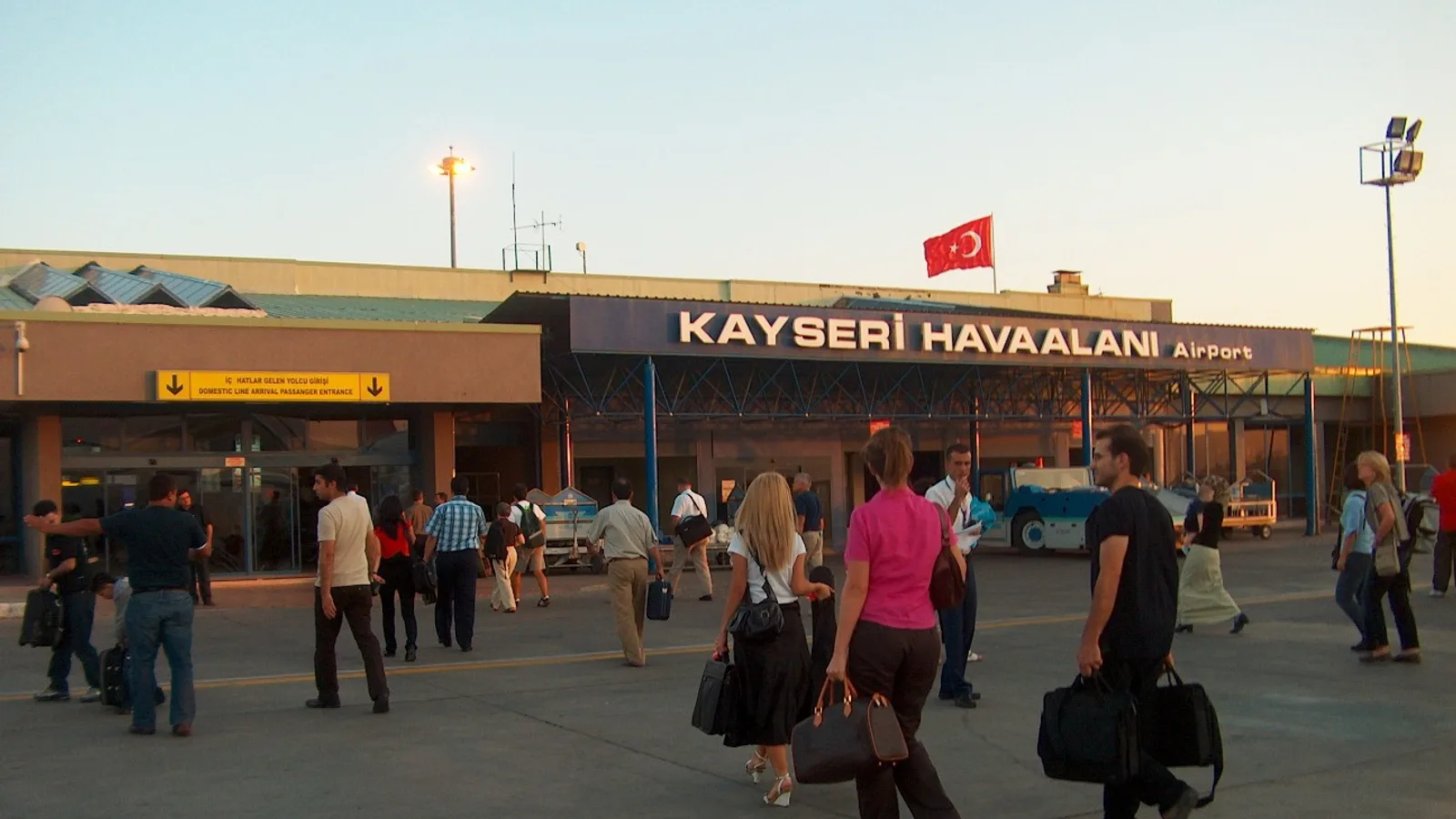 Kayseri Havaalanı binası ve havaalanı alanında yürüyen yolcular.