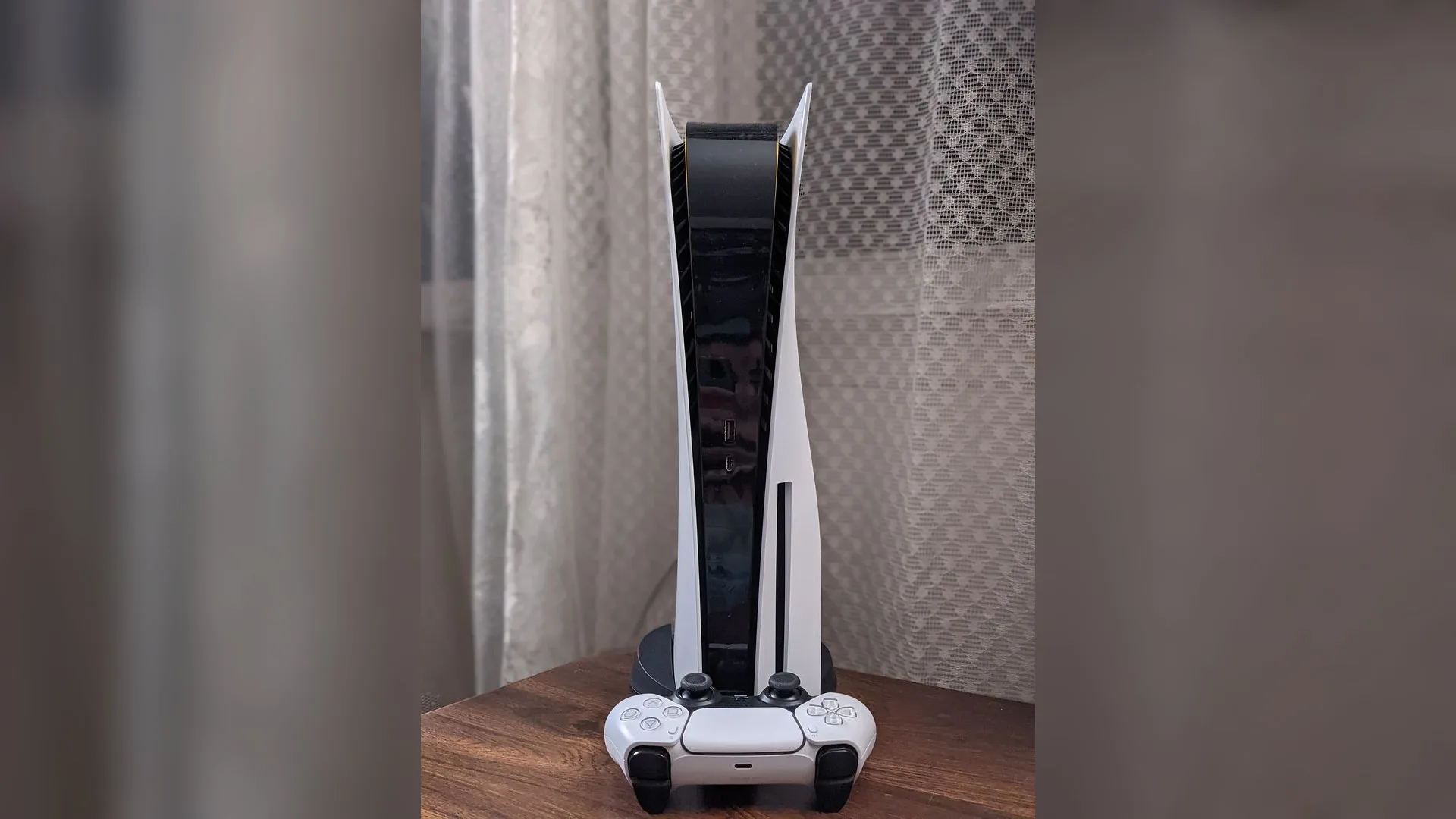 Beyaz ve siyah renkli PlayStation 5 kontrolcüsü ve konsolu.