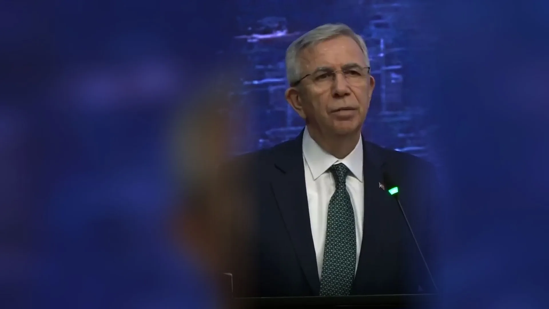 Ankara Büyükşehir Belediye Başkanı Mansur Yavaş, mavi ekran önünde kürsüde konuşurken.