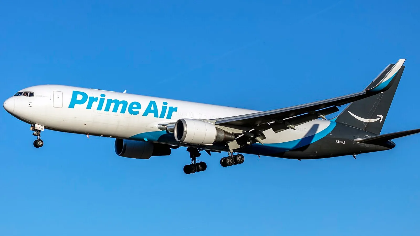 PrimeAir logolu beyaz ve mavi kargo uçağı gökyüzüne karşı iniş yapıyor.