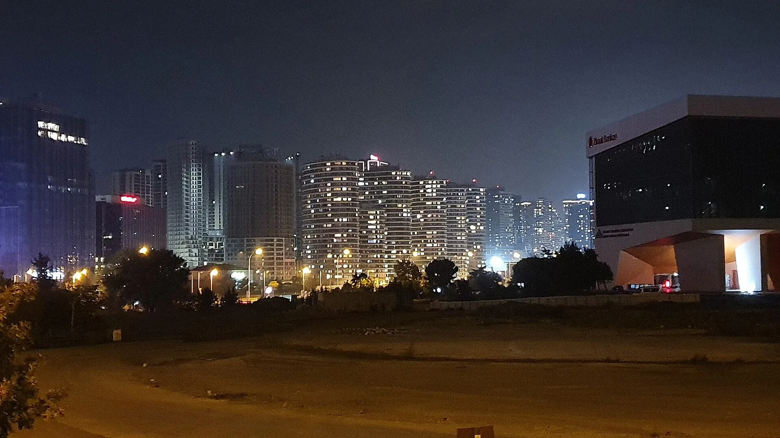 Gece manzarasında aydınlatılmış gökdelenler ve boş alan.