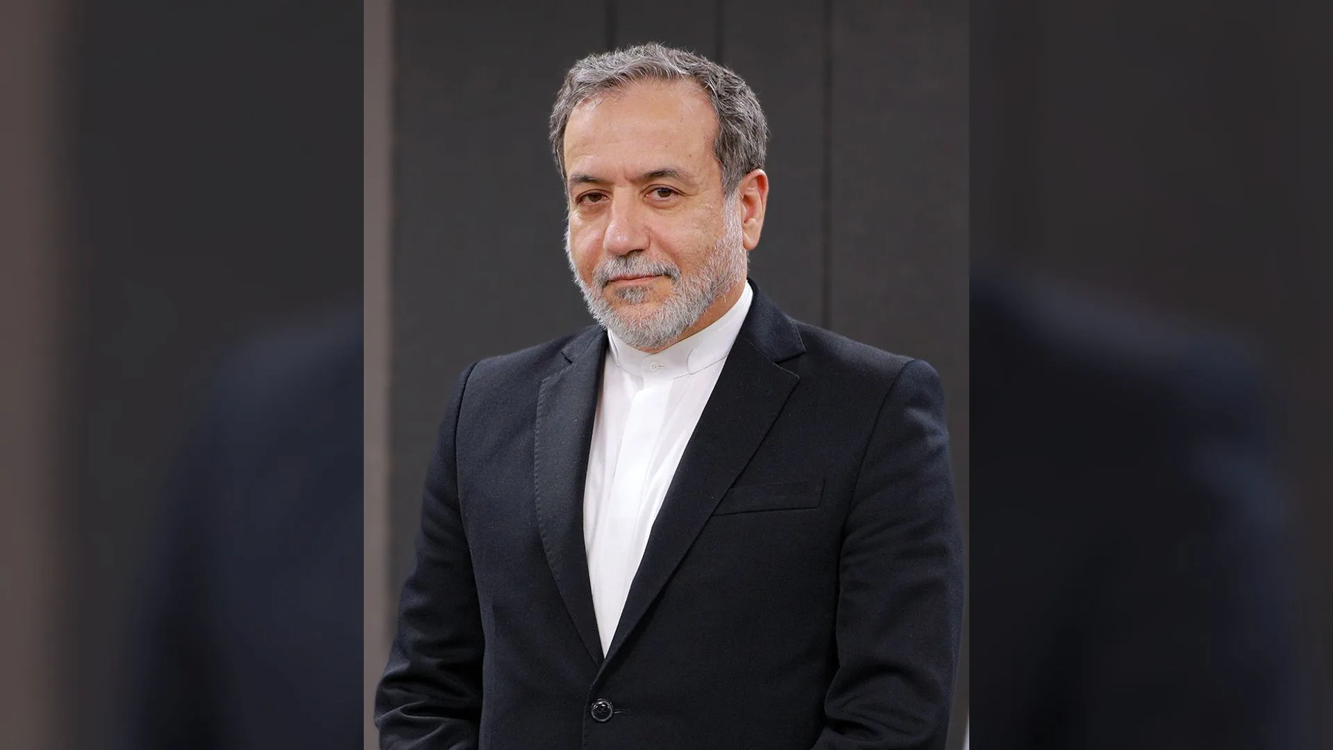 Siyah takım elbise ve beyaz gömlek giymiş, gri sakallı bir adam