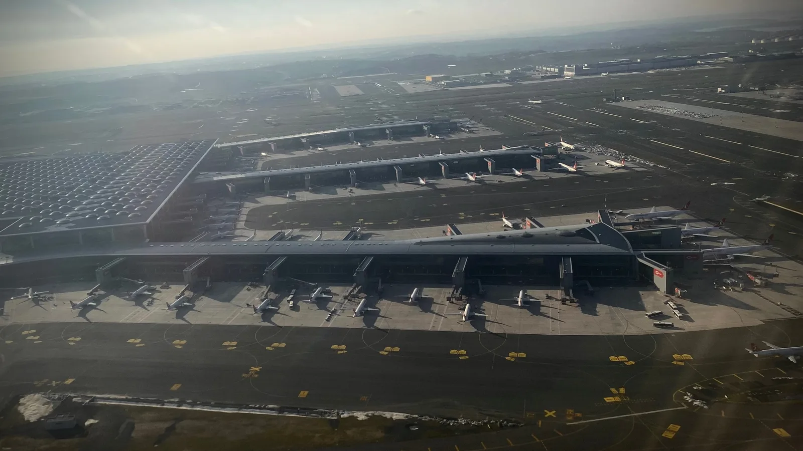 İstanbul Havalimanı'nın terminal binası ve kapılara yanaşmış çok sayıda yolcu uçağı, havadan görünüm.