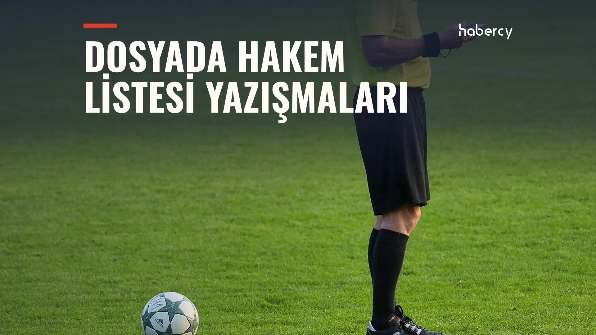 Yeşil sahada siyah şortlu bir hakem ayakta duruyor, önünde bir futbol topu var