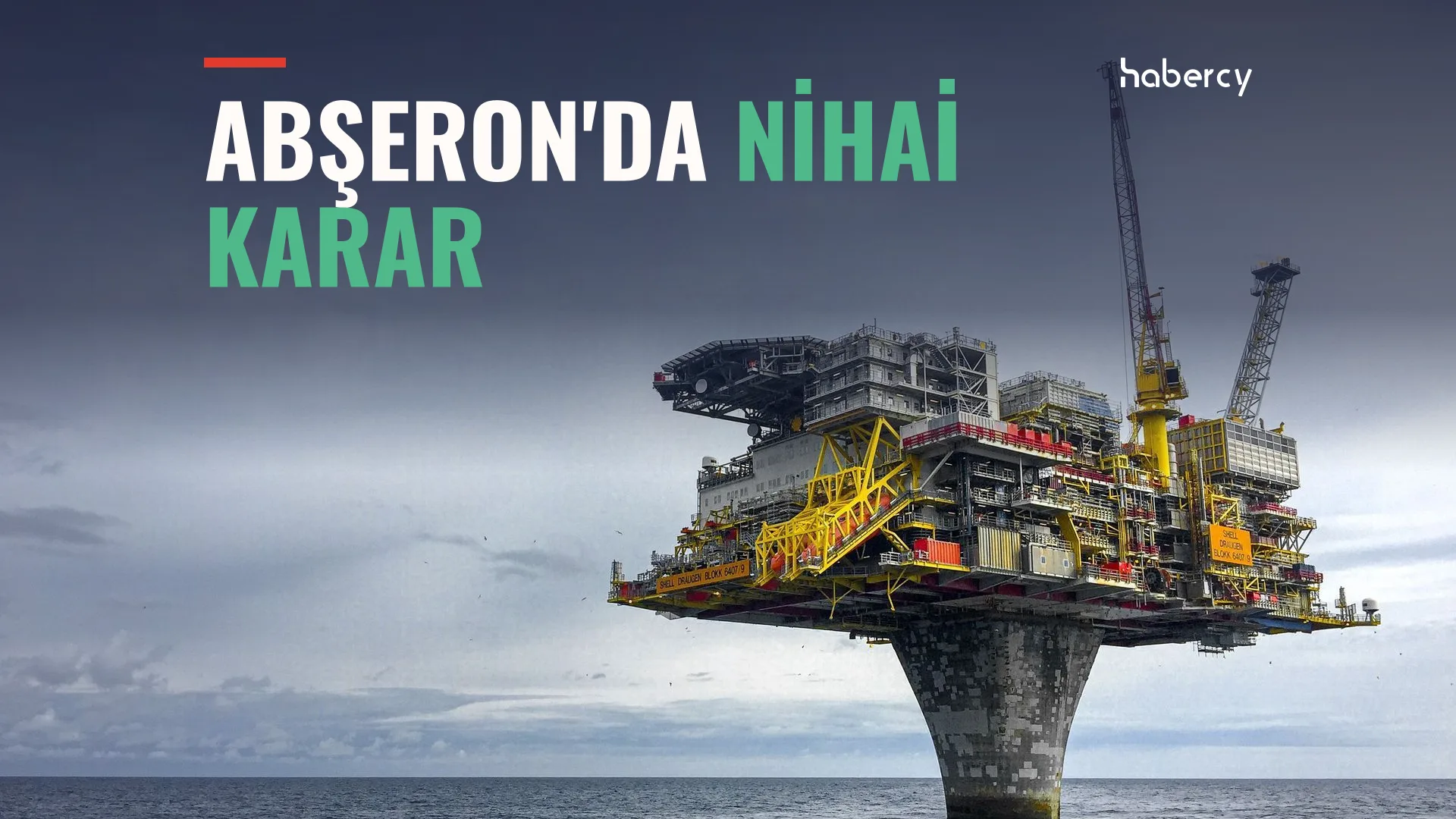 Bulutlu gökyüzü altında denizin ortasında tek beton ayak üzerinde yükselen, sarı vinçli açık deniz platformu