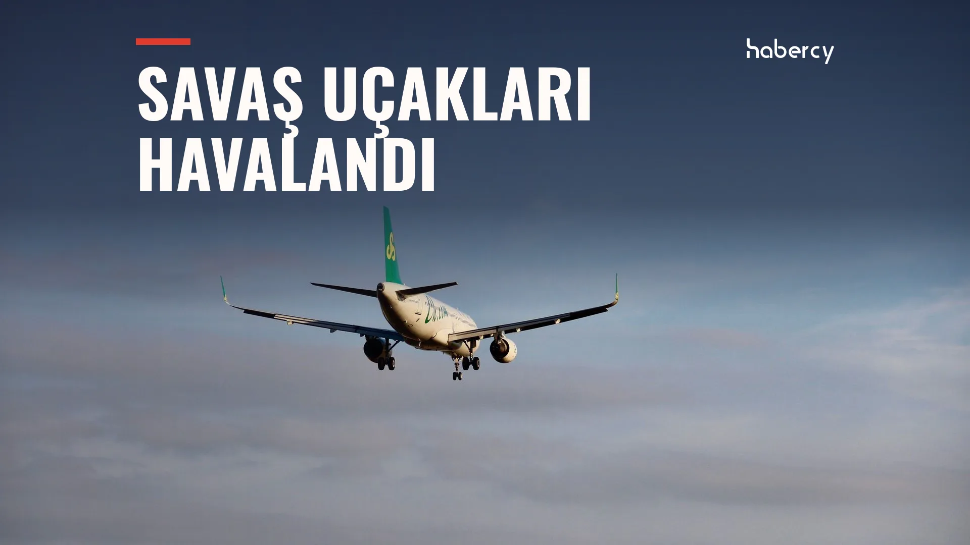 Bulutlu gökyüzünde iniş takımları açık, yeşil kuyruklu bir yolcu uçağı