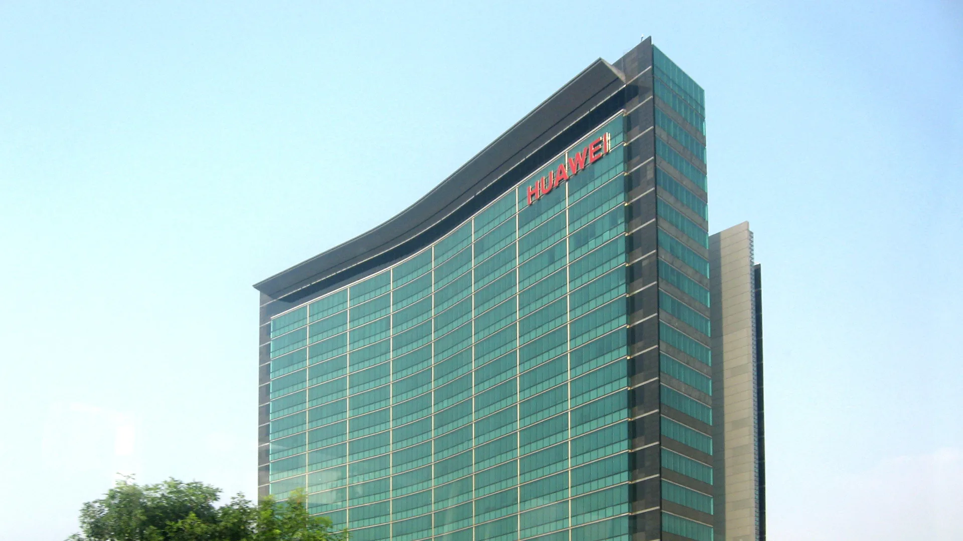 Cephesinde kırmızı Huawei yazısı bulunan yeşil camlı kavisli gökdelen