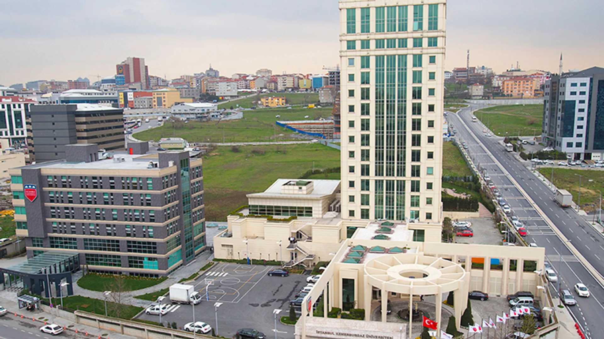 Otoyol kenarında yüksek bir kule, girişinde bayraklar ve İstanbul Kemerburgaz Üniversitesi tabelası