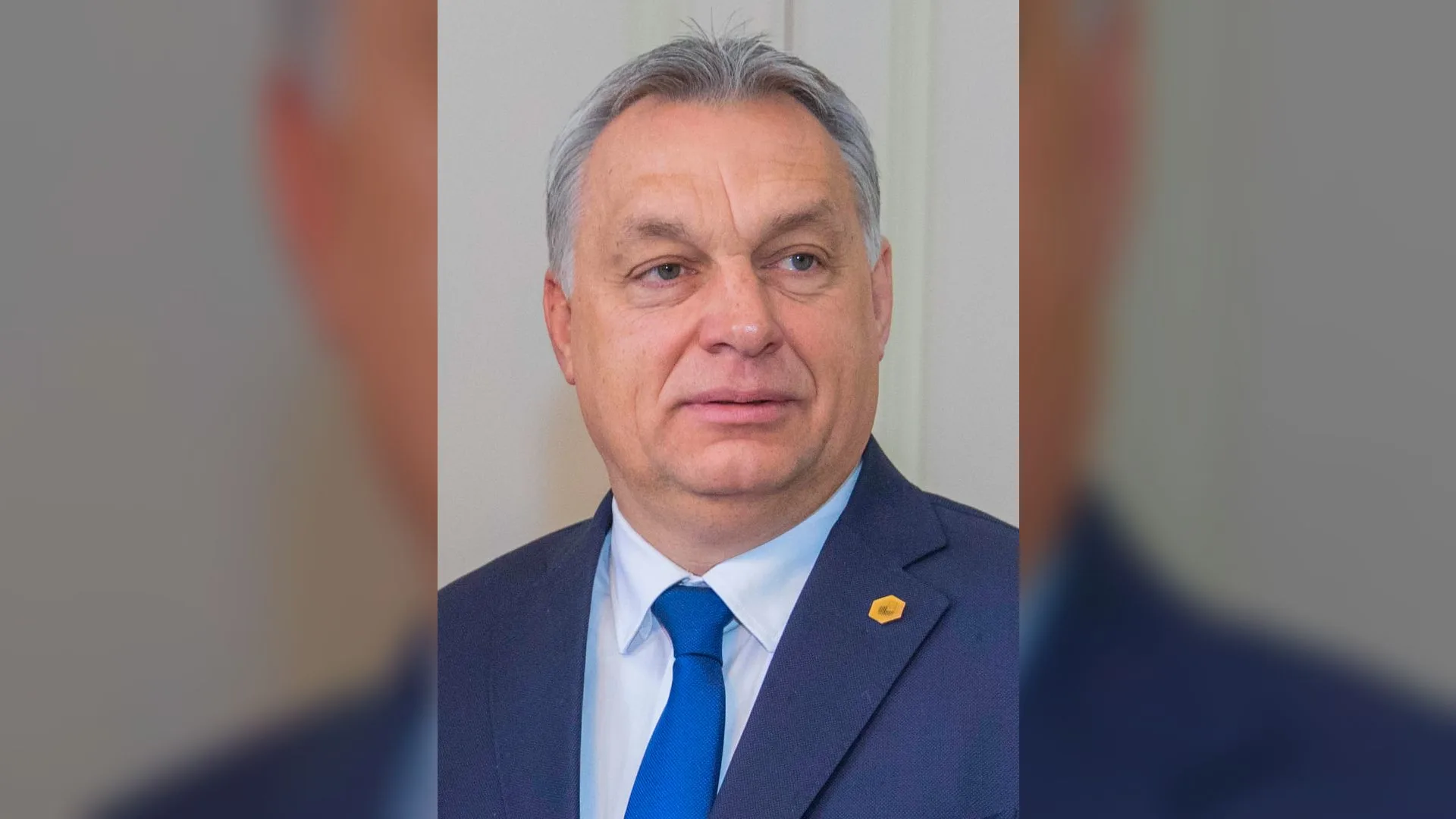 Lacivert takım elbiseli, mavi kravatlı, gri saçlı bir adamın portresi