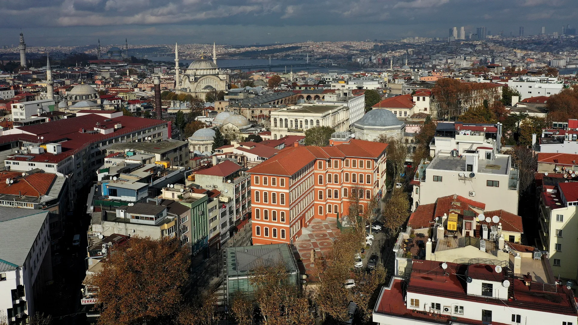 Camiler ve kırmızı çatılı binalar arasında turuncu tarihi bir binanın havadan görünümü